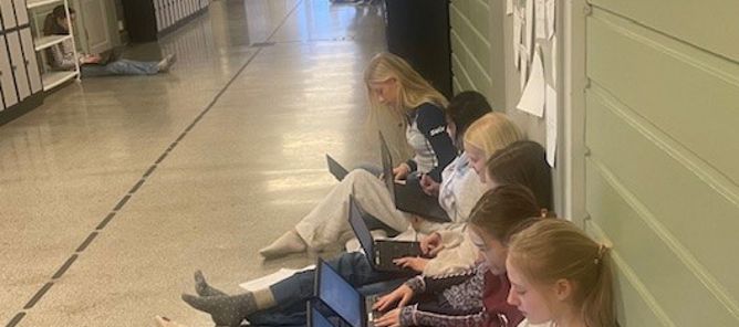 en gruppe personr som sitter på gulvet og bruker bærbare datamaskiner 