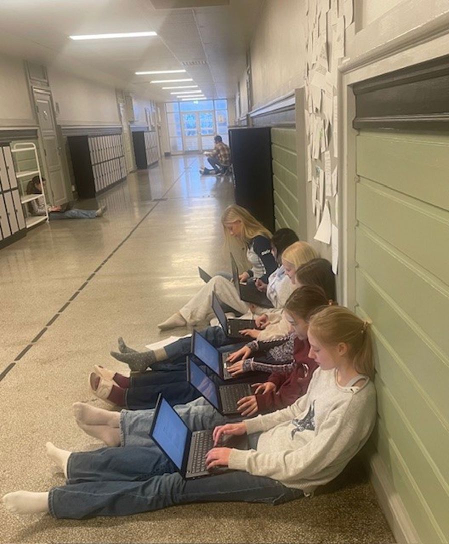 en gruppe personr som sitter på gulvet og bruker bærbare datamaskiner 