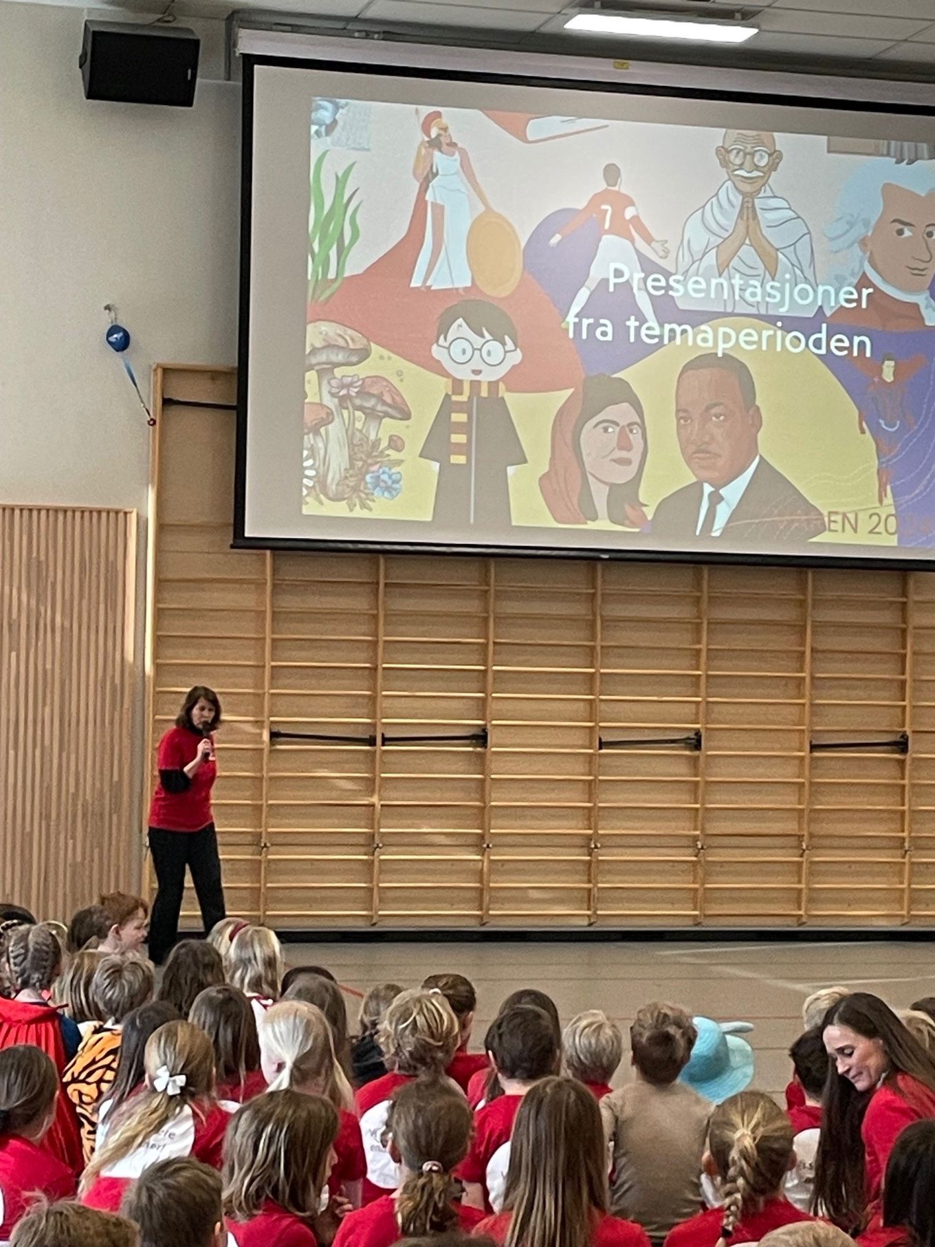 en person som står foran en skjerm foran en gruppe barn