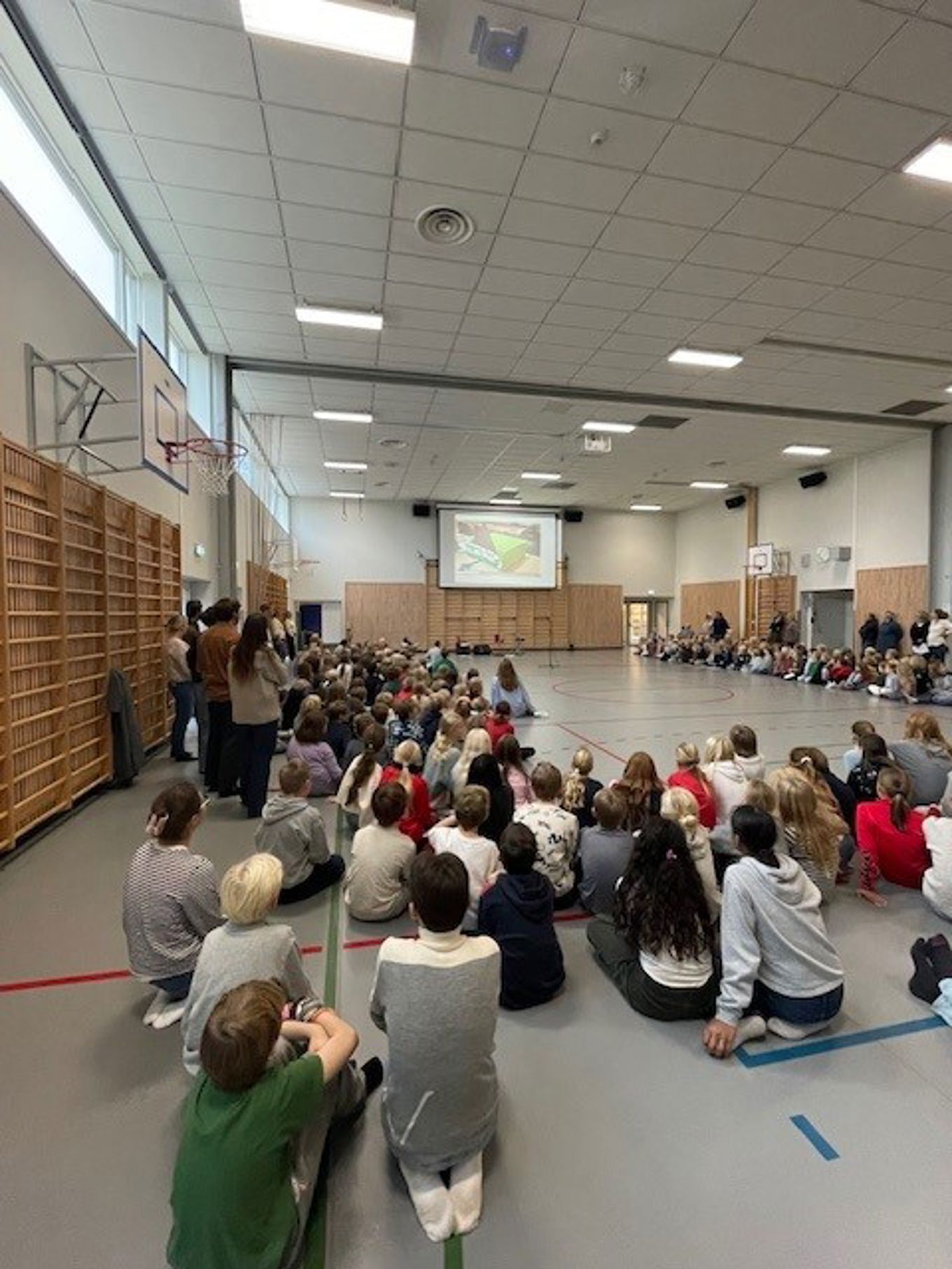 en gruppe mennesker som sitter i et rom med en skjerm og en projektorskjerm en gruppe mennesker som sitter i et rom med en skjerm og en projektorskjerm