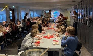 en gruppe mennesker som spiser grøt i kantinen